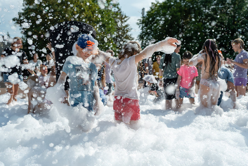 Children running through a Coastal foam party