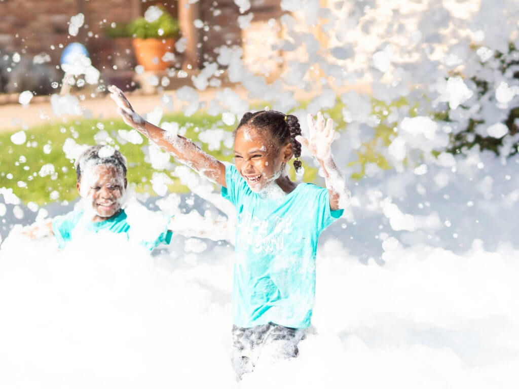 Children playing beneath a foam cannon